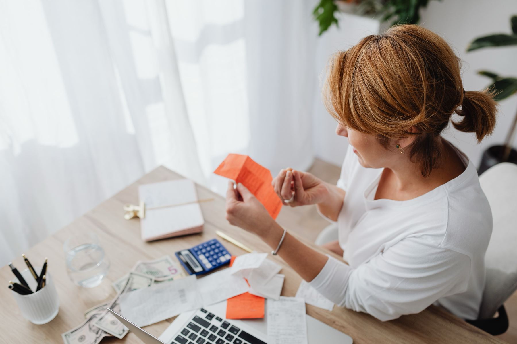 Small business owner checking receipts with a calculator at her desk